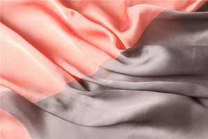 Vista dettagliata del tessuto satinato rosa corallo e grigio con trama setosa
