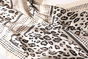 Detailed close-up showing leopard print silk scarf texture and elegant drape folds
