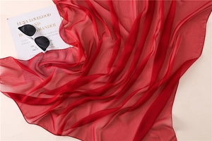 Primer plano de la textura del pañuelo de gasa roja con elegante caída semitransparente