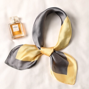 Dettaglio di un elegante foulard in seta grigio e giallo dalla trama liscia e lucida