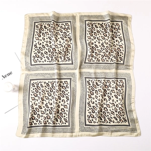 Detailed view of square satin scarf with leopard print blocks and geometric borders