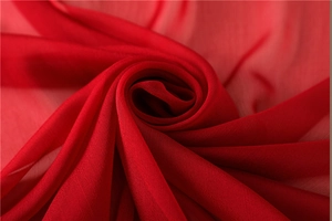 Primer plano macro de bufanda de gasa rojo oscuro drapeada en forma de rosa espiral