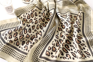 Detailed view of leopard print silk scarf with black polka dots and smooth texture