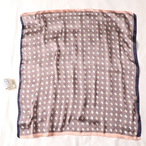 Detail of silk square scarf with horse head pattern and contrast border on white background