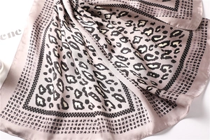 Detail of silk-like leopard print scarf featuring geometric borders and soft drapes