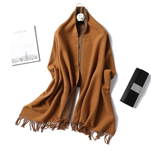 Close-up of caramel cashmere-like scarf with fringe tassels and soft knit texture