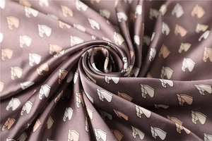 Close-up of brown satin scarf featuring a detailed horse print and silky texture