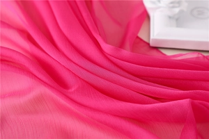 Detalle de la textura plisada de seda sintética rosa con un acabado ligero y transparente