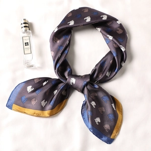 Satin silk scarf with horse head print and gold trim in a stylish knotted display