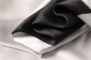 Macro del drappeggio morbido e della lucentezza perlata del raso di seta bianco e nero