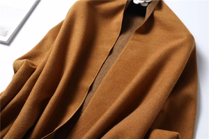 Close-up of caramel cashmere-feel scarf showing soft texture and thick tassels