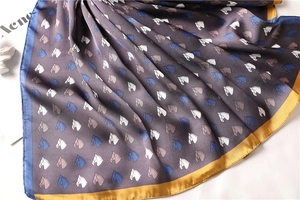 Detail of silk square scarf with horse pattern print and elegant satin sheen texture