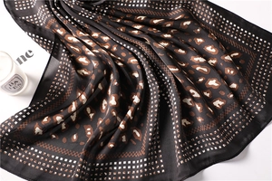 Detail of silk-like leopard print scarf with geometric borders and smooth texture