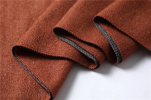Detail shot of caramel cashmere scarf texture with fine stitching and grey reverse layer