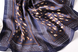Macro view of leopard print silk scarf showing smooth texture and geometric patterns