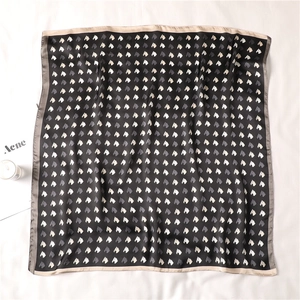 Detailed view of square silk scarf featuring horse head prints and champagne satin edges