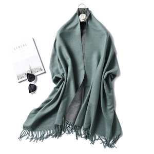 Detail of gray-green cashmere-like scarf with dense tassels and double-sided color design