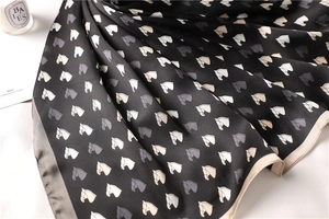 Close-up of black silk scarf with elegant horse print and premium satin texture