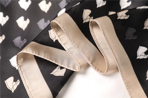 Detail of silk scarf showing abstract leaf print and refined champagne stitched hem