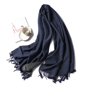 Flat lay of navy and grey cashmere-like scarf with fringe near a coffee cup and magazine
