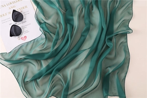 Dettaglio della texture della sciarpa in chiffon verde scuro con pieghe eleganti