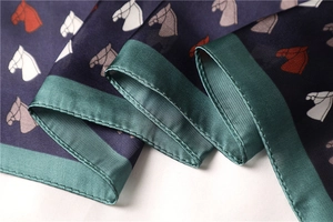 Detail of silk scarf showing horse head prints and precision green satin edge stitching