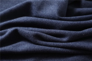 Macro view of thick dark blue cashmere-like fabric showing soft texture and tassels