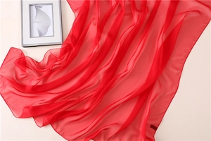 Dettaglio di sciarpa in chiffon rosso con trama traslucida e cucitura a bordo arrotolato