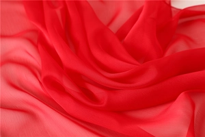 Dettaglio del tessuto in chiffon rosso semitrasparente con trama fine e drappeggio