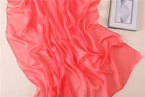 Detalle de un pañuelo de seda rosa coral ligero con bordes enrollados y caída suave