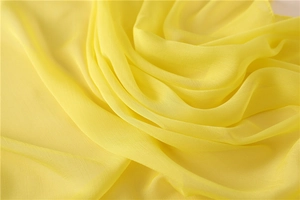 Macro di sciarpa in chiffon giallo che mostra la trama fine e le morbide pieghe