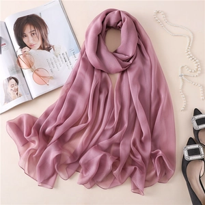 Primer plano de un chal rosa palo con collar de perlas y accesorios de moda