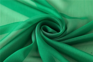 Dettaglio macro dello scialle in chiffon verde smeraldo con trama traslucida e pieghe