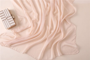 Detalle macro de la elegante bufanda rosa nude con pliegues suaves y textura fina