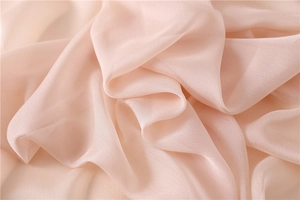 Detalle de tela sedosa rosa claro que muestra una suave textura arrugada y transparente
