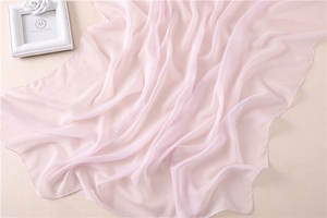 Detalle macro del pañuelo rosa claro en tejido transparente con texturas plisadas suaves