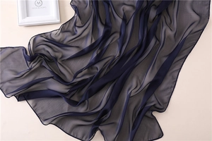 Detalle de bufanda de gasa azul marino con bordes enrollados finos y textura suave seda