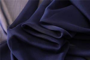 Primer plano de bufanda de seda azul oscuro con textura suave y patrón ondulado