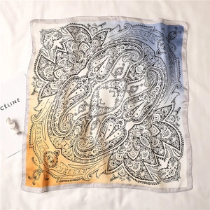Detailed macro view of the soft paisley silk scarf with elegant orange to blue gradient