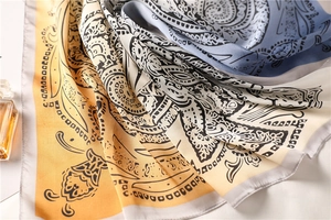 Detailed macro view of the silky paisley pattern and draped texture on the square scarf