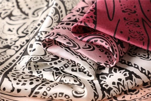 Close-up of silky paisley square scarves in cream, pink, and burgundy shades