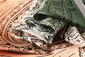 Macro view of silky dual-tone scarf featuring vintage paisley patterns and soft textures