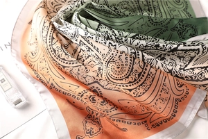 Close-up of paisley pattern gradient silk scarf with soft textures and orange green tones