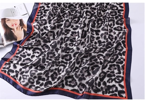 Detail of leopard print silk scarf featuring navy blue edges and orange stripe accents