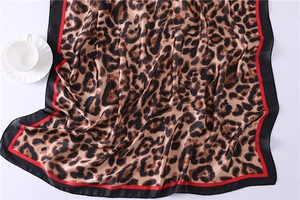 Detail of leopard print silk scarf with red stripe and black borders on white background