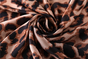 Macro shot of silk leopard print fabric showing smooth texture and satin luster finish