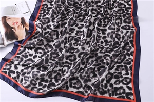 Detail of leopard print silk scarf with stylish navy and orange contrast striped borders