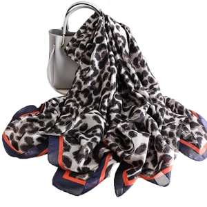 Classic leopard print silk scarf with orange contrast border draped over a handbag