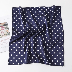 Detail of navy blue polka dot silk scarf showing smooth texture and edge stitching