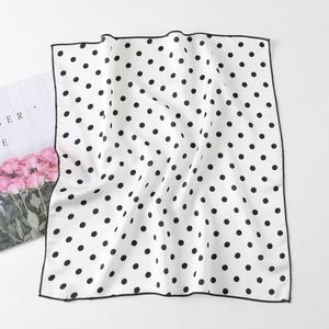 Detail of silk-satin square scarf featuring classic black polka dots on white fabric
